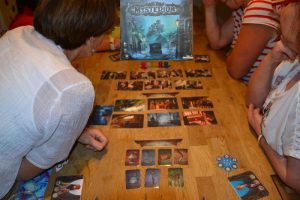 Bild: drei Spieler, am Tisch sitzend mit aufgedeckten Spielekarten