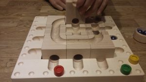 Bild: Holzbahn mit Murmeln und Spielsteinen