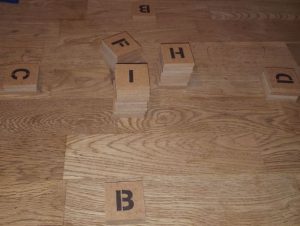 Bild: Holzplättchen mit Buchtaben übereinander gestapelt oder einzeln auf Tisch