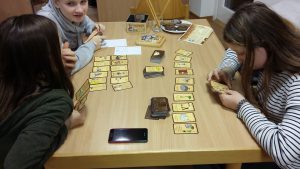 Bild: Kinder um einen Tisch sitzend beim gemeinsamen Spiel mit Karten