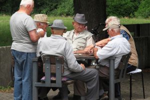 Bild: ältere Männer sitzen am Tisch unter einem Baum beim gemeinsamen Spiel beisammen