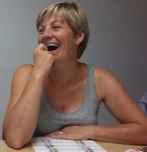 Bild: lachende Frau, die einen Spielplan vor sich liegen hat