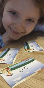 Bild: Mädchen mit Spielkarten, auf denen Zahlen aufgedruckt sind