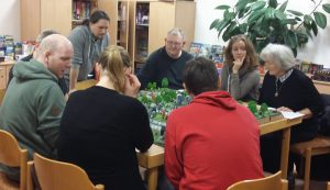 Bild: 7 Spieler sitzen um einen Spieletisch