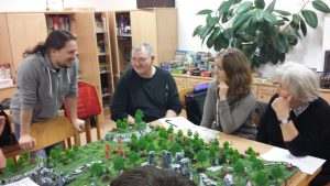 Bild: spieler sitzen an einem Spieletisch und unterhalten sich