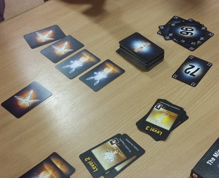 Bild: auf einem Tisch liegen aufgedeckte Spielkarten mit Zahlen und Symbolen, zusätzlich ein verdeckter Stapel