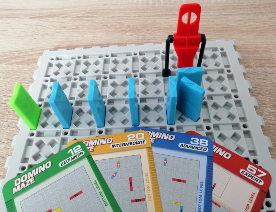 Spielbrett mit Dominosteinen und Beispiele der vier Schwierigkeitsstufen.