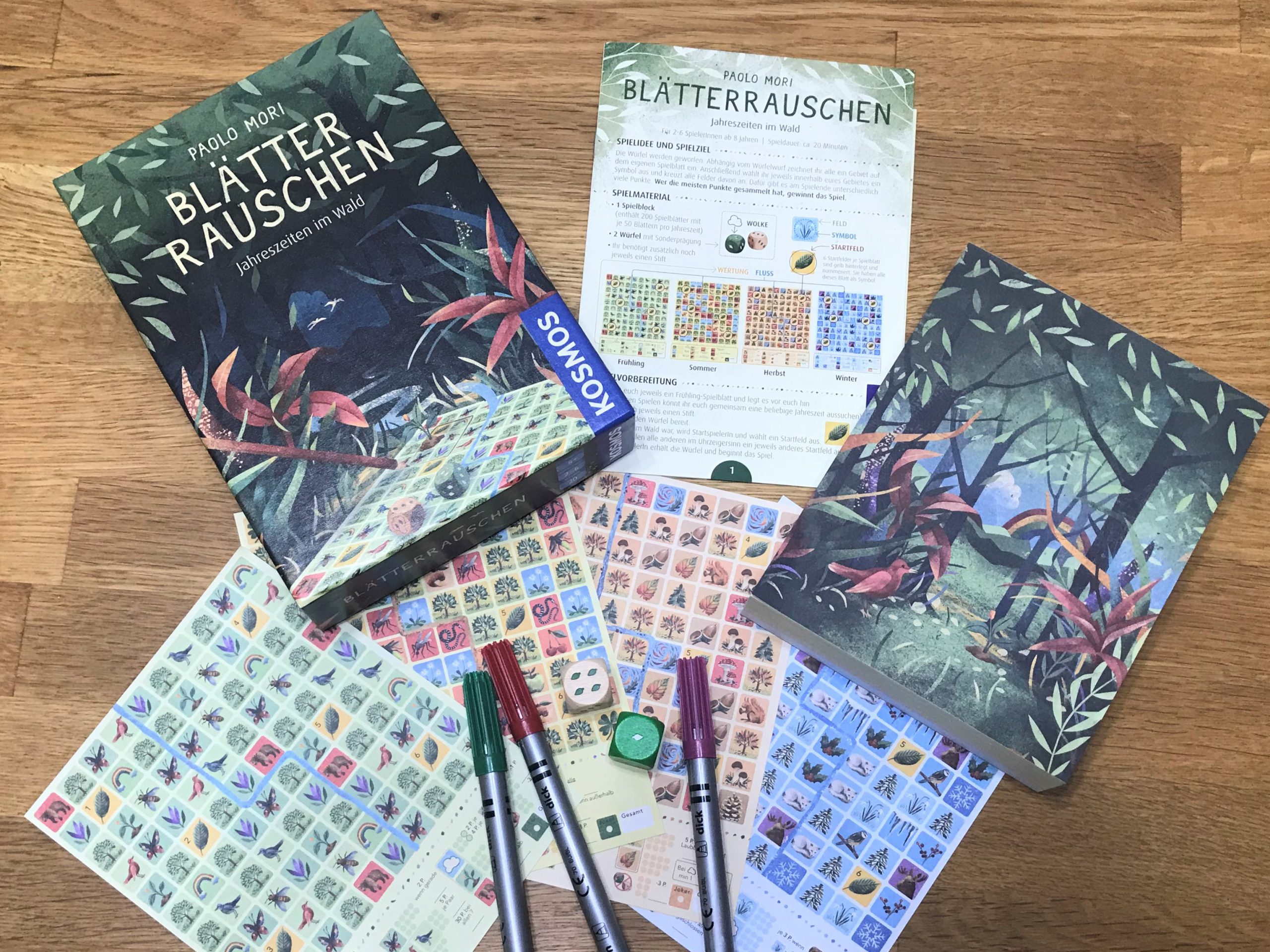 Ein Blick auf die vier unterschiedlichen Spielbögen, zwei Würfel und Stifte