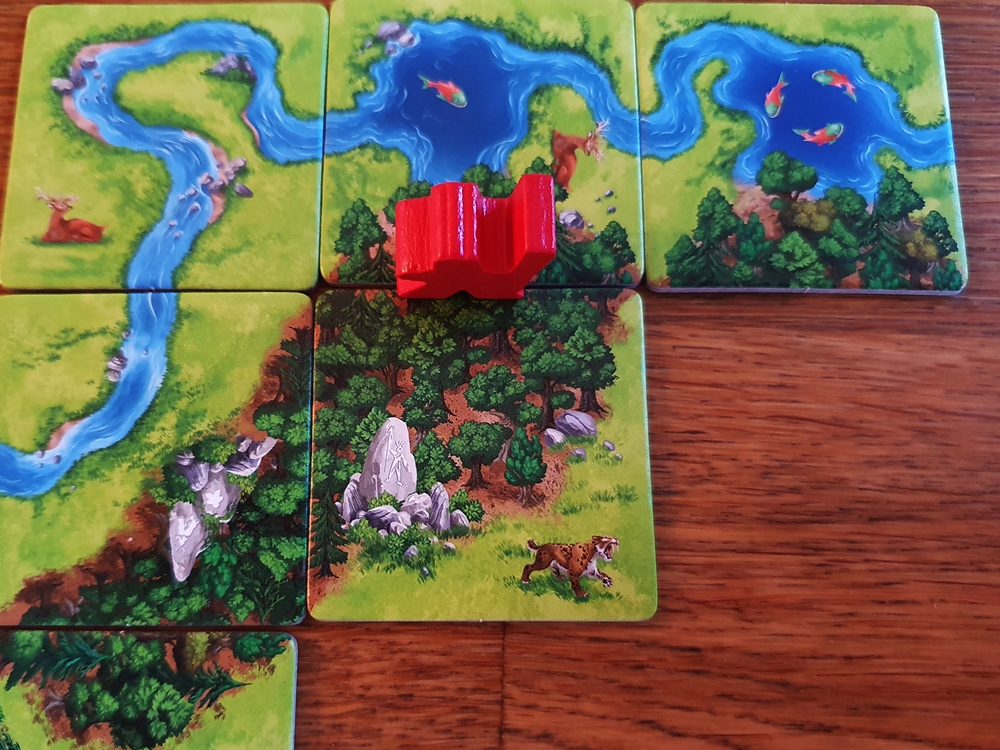 Gelegte Spielplättchen Wald und Fluss, eine Spielfigur