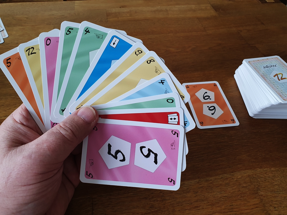 Hand mit 12 Karten zu Spielbeginn, im Hintergrund Ablage- und Nachziehstapel