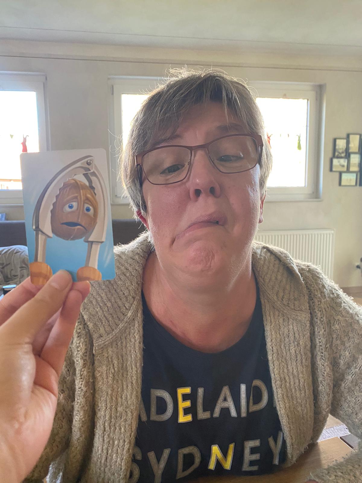 Zu sehen ist eine Frau, die eine abgebildete Emotion nachahmt.