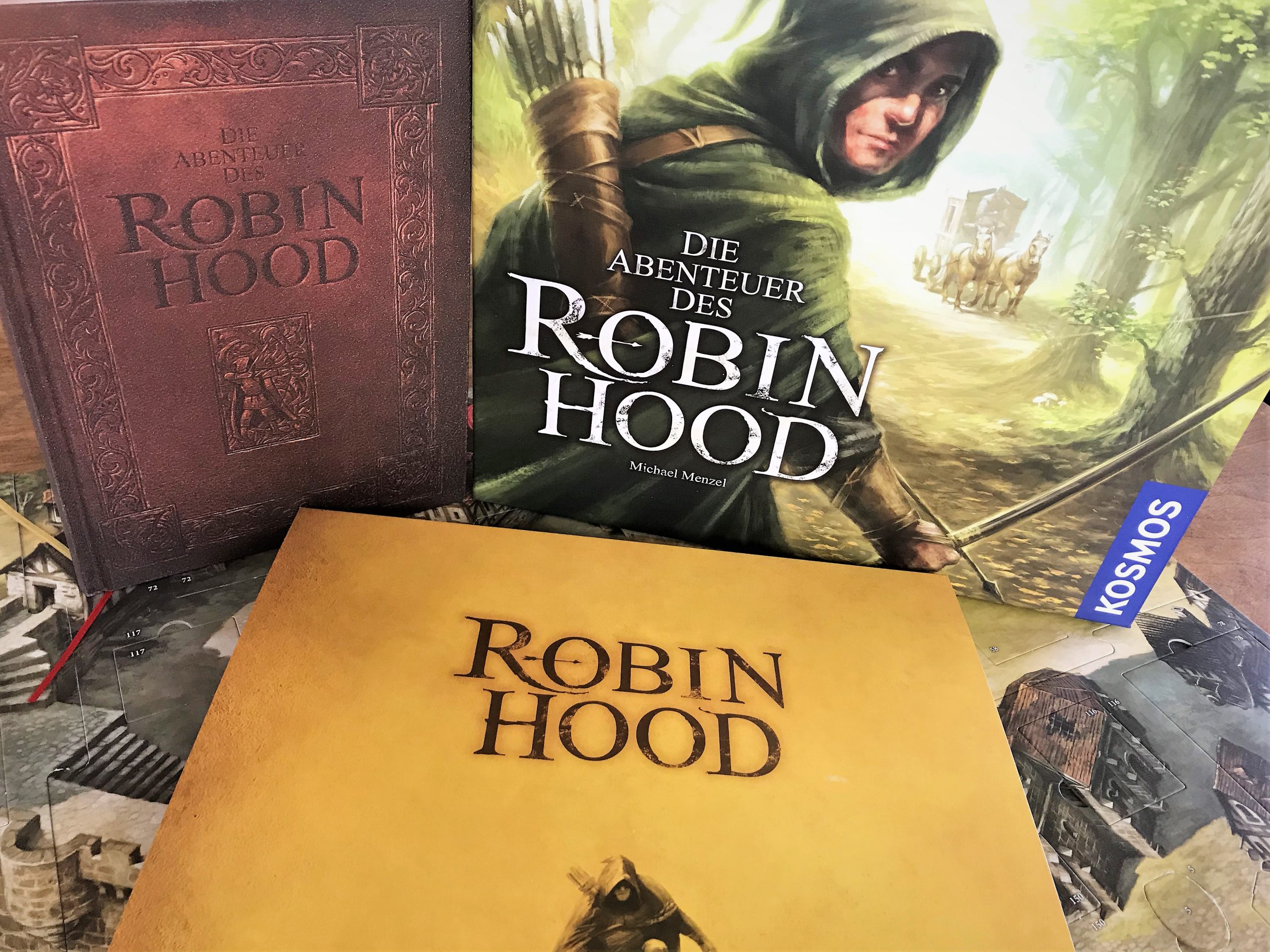 EIn Block auf die Schachtel, das Abenteuerbuch und den Schuber des Spielplans.