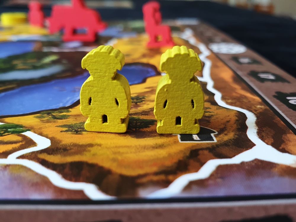 Zwei gelbe Kriegerfiguren auf einem Savannenfeld