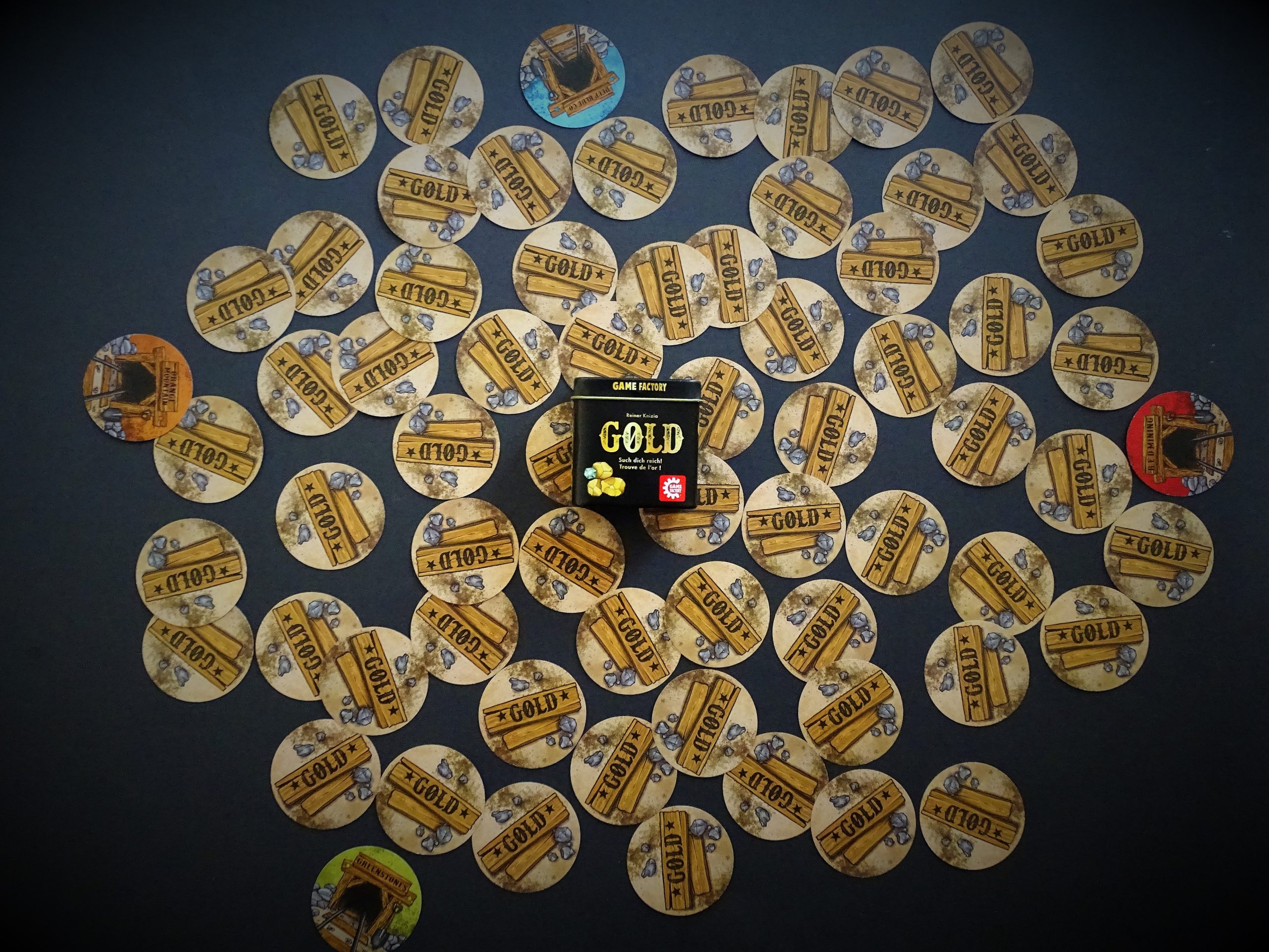 Die kleine Spielkiste liegt inmitten der runden Spielkarten.