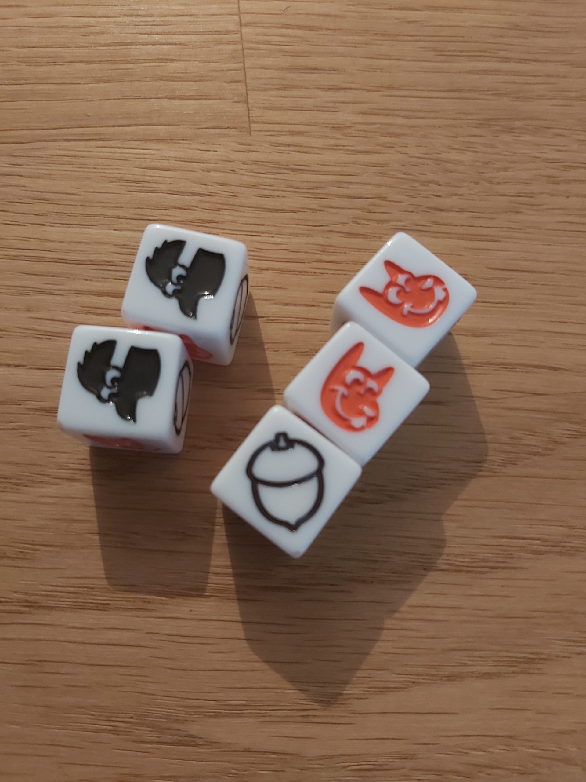 Zu sehen sind die Nusswürfel aus auf die Nüsse, die entweder eine schwarze Nuss, einen schwarzen Tannenhäher oder ein orangenes Eichhörnchen zeigen.