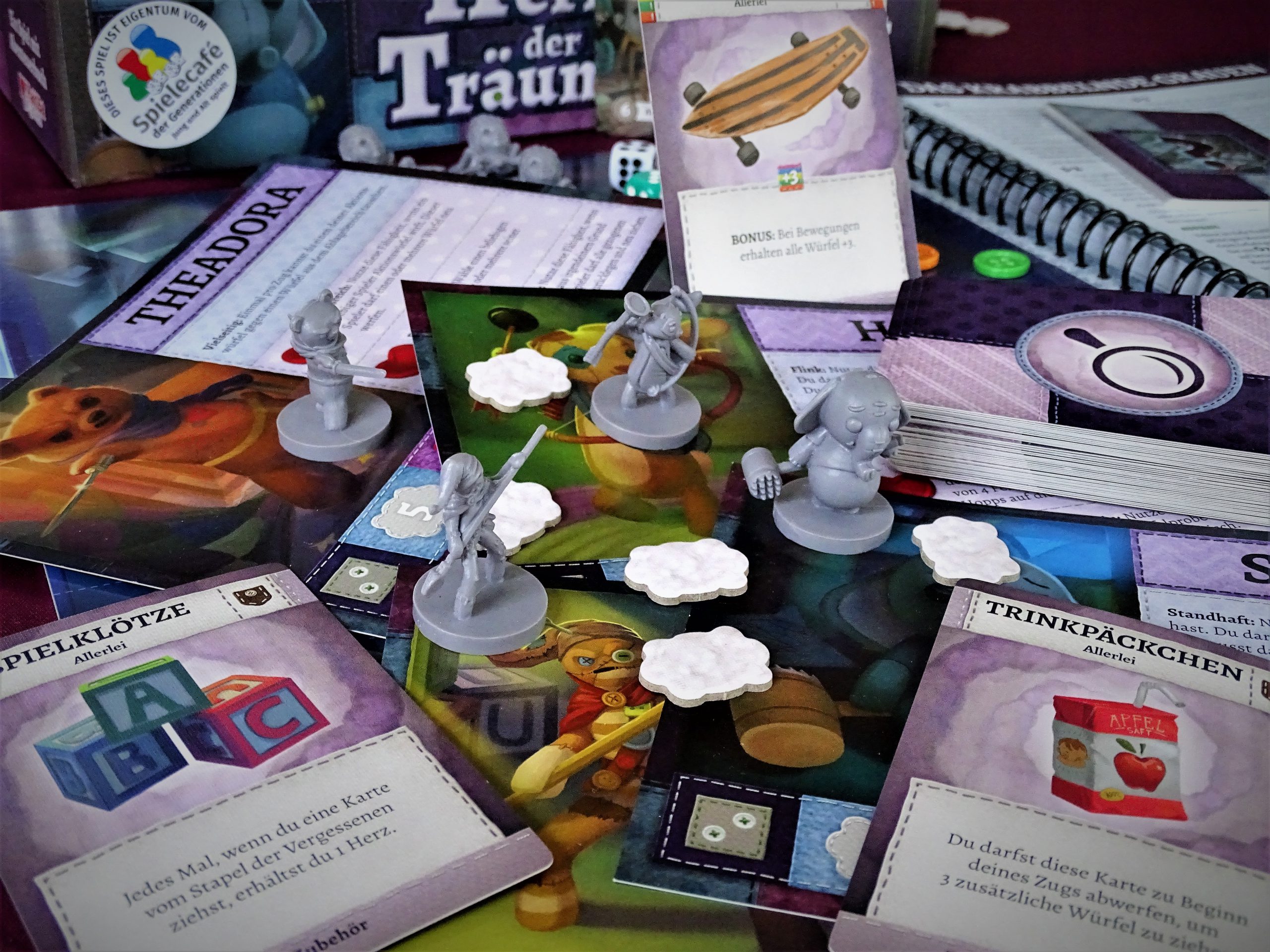 Die Miniaturen der vier Stoffis sind inmitten von Spielmaterial aufgebaut. 