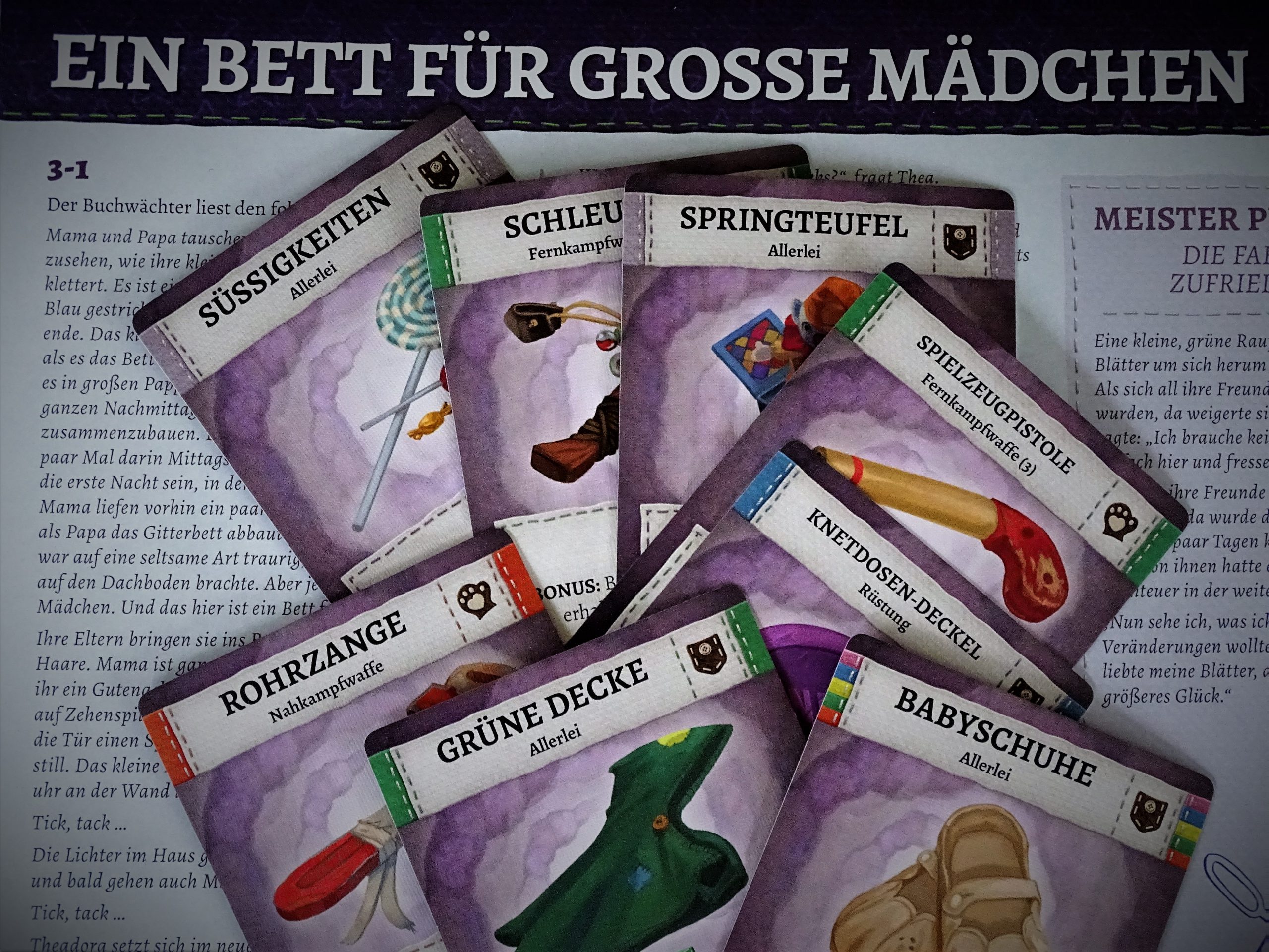 Ausrüstungskarten liegen auf dem Abenteuerbuch. 