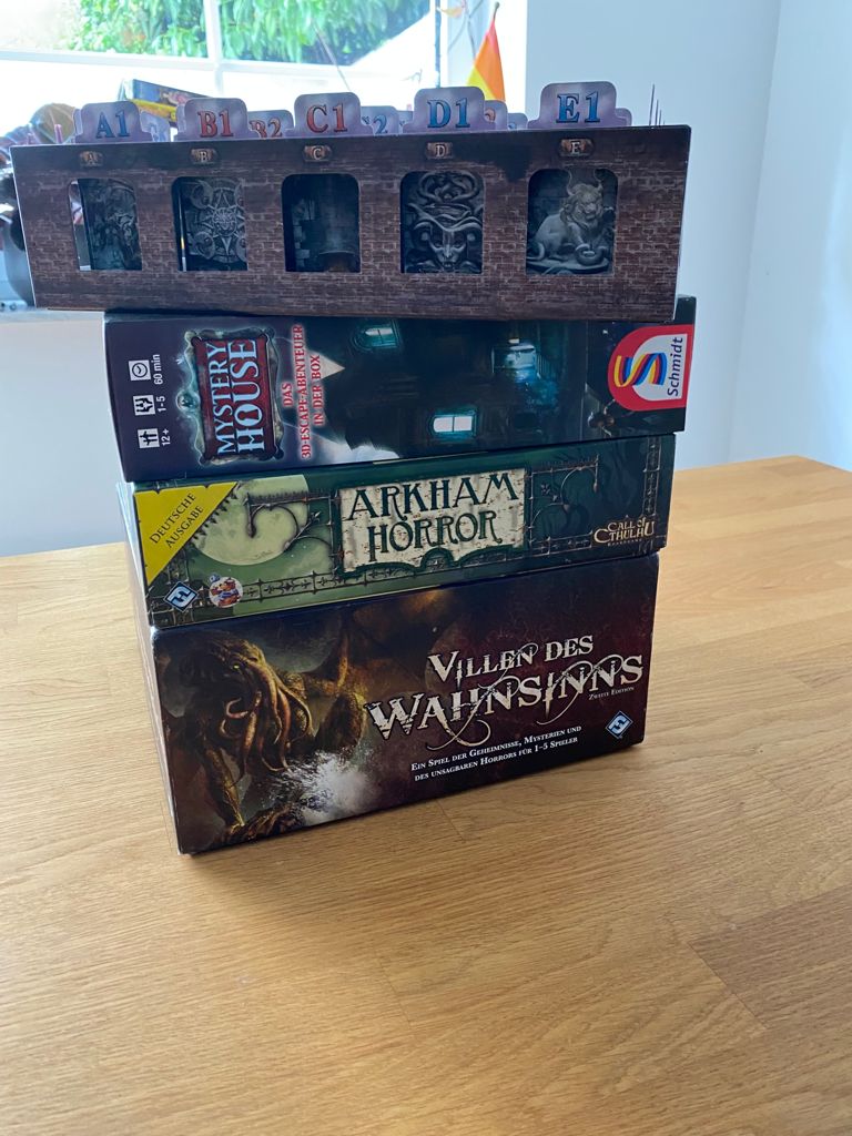 Zu sehen ist das Spiel auf anderen Spielekartons gestapelt.