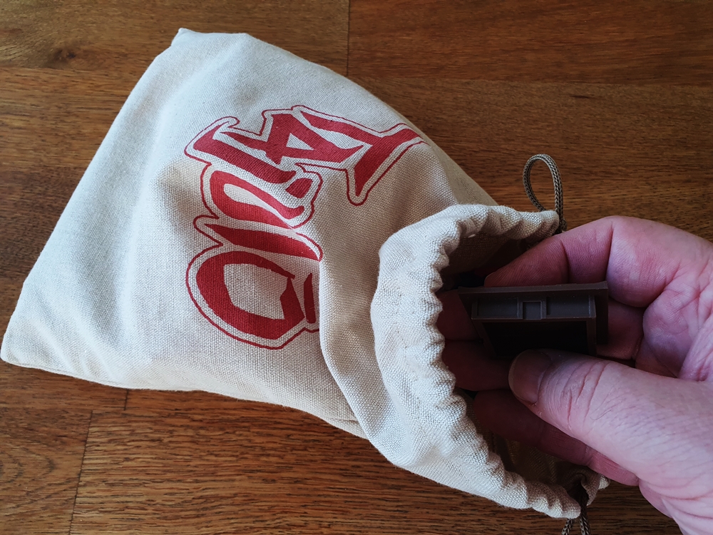 Eine Hand zieht ein Etagenplättchen aus dem Beutel.