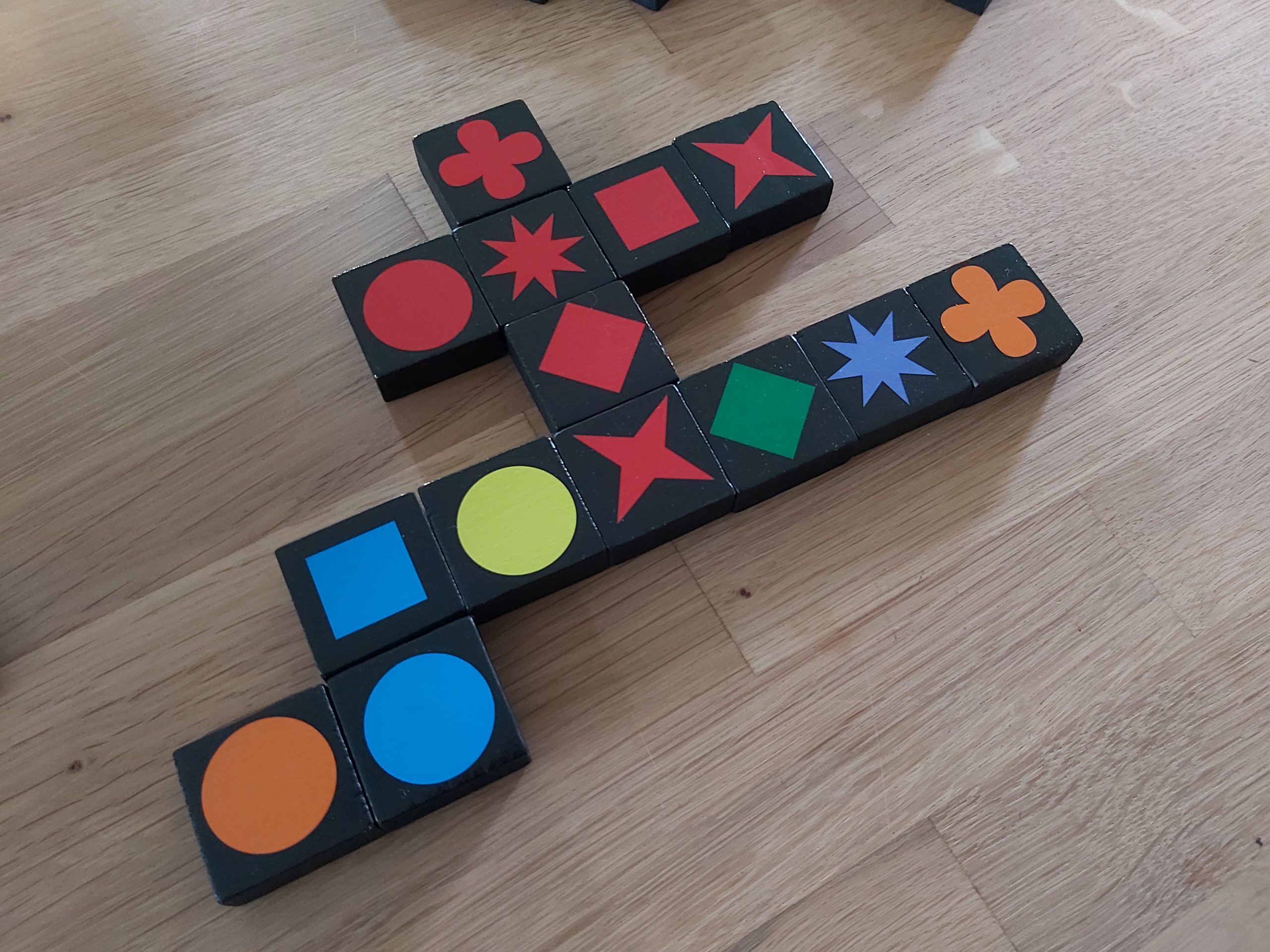 Zu sehen ist ein langsam entstehenden Steingeflecht der Qwirkle-Steine