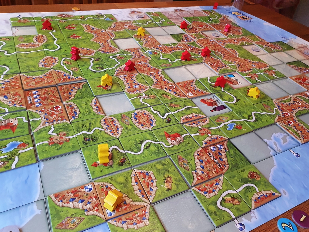 Gegen Spielende fast ausgefüllter Plan, darauf Meeple in Gelb und Rot