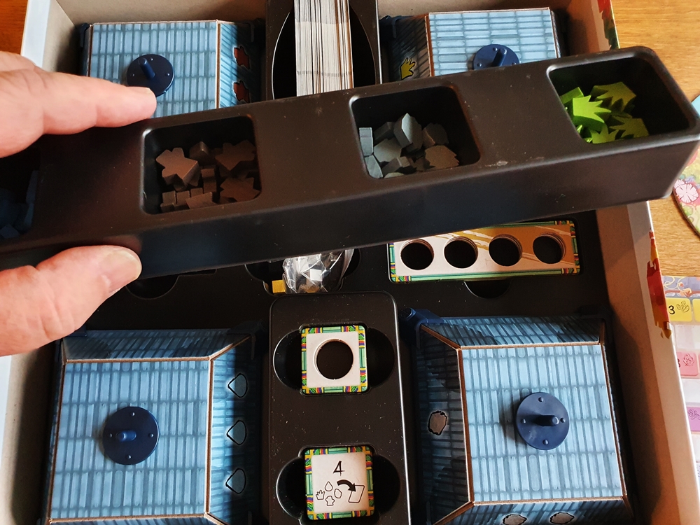 Das Material im Inlay des Kartons. Eine Hand hebt die Leiste mit den Ressourcenbehältern