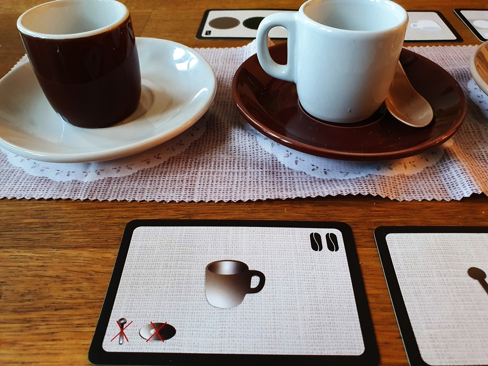 Untertassen weiß und dunkelbraun, die Tassen darauf entgegengesetzt. Die Aufgabenkarte verlangt eine Tasse allein