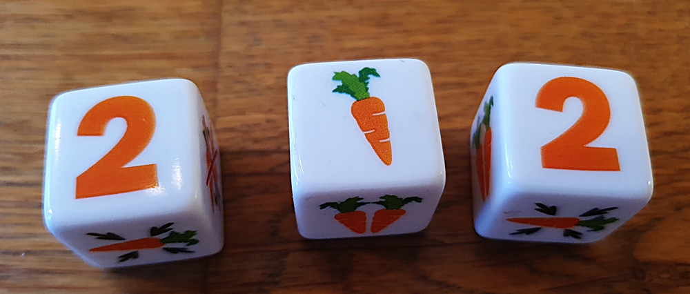 Drei Würfel, zwei zeigen eine Zwei, einer zeigt eine Karotte
