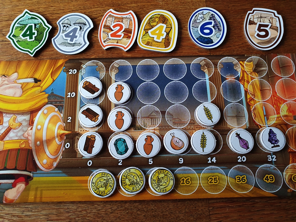 Spielertableau mit gesammelten Stadtmarken, Ressourcenmarken und Münzen