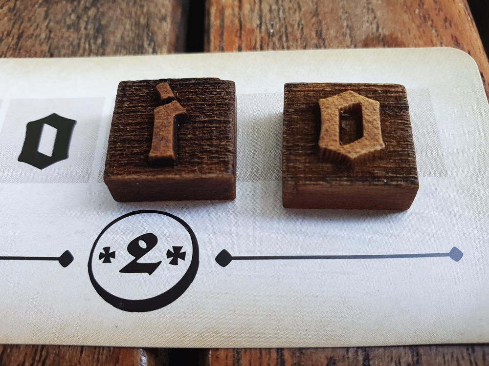 Zwei Lettern aus Holz liegen auf einem Druckauftrag