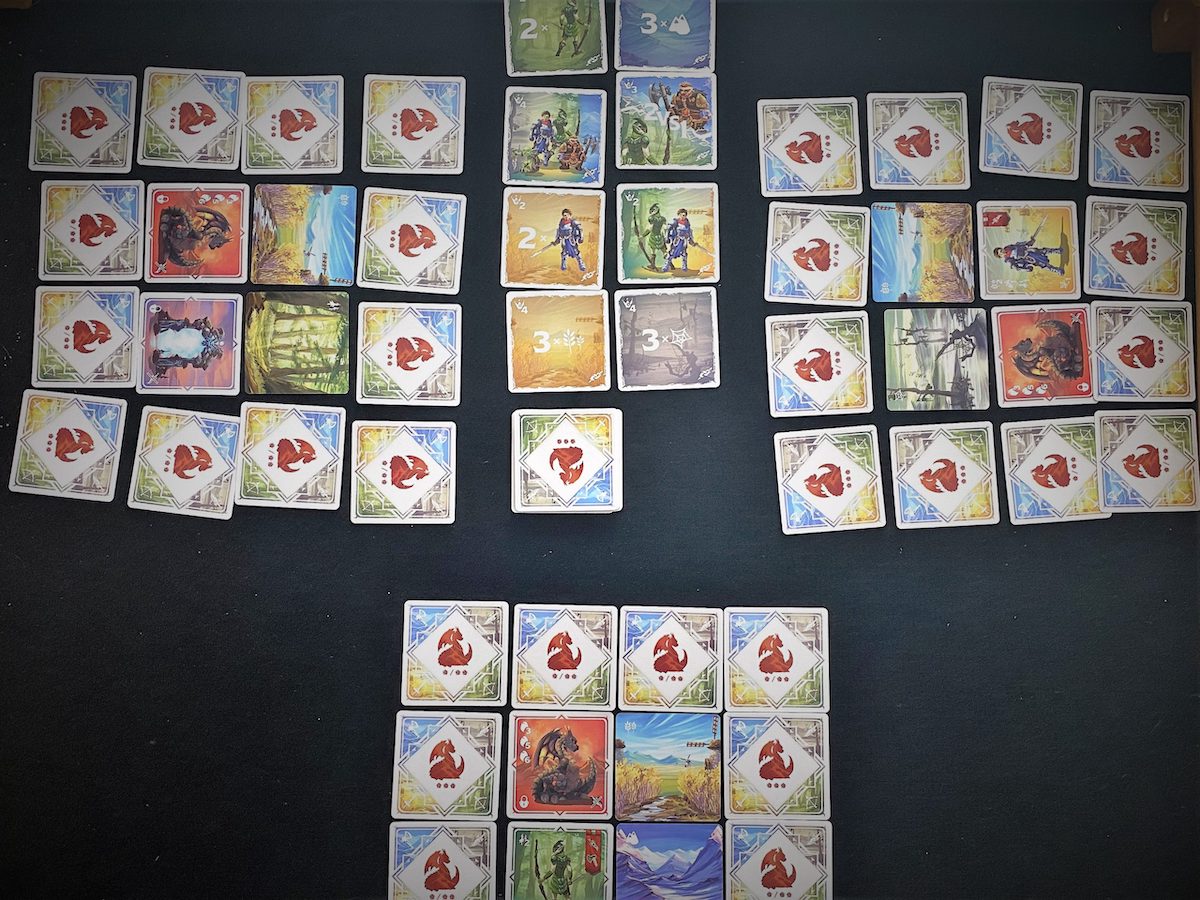 Der Spielaufbau für drei Personen liegt auf dem Tisch.