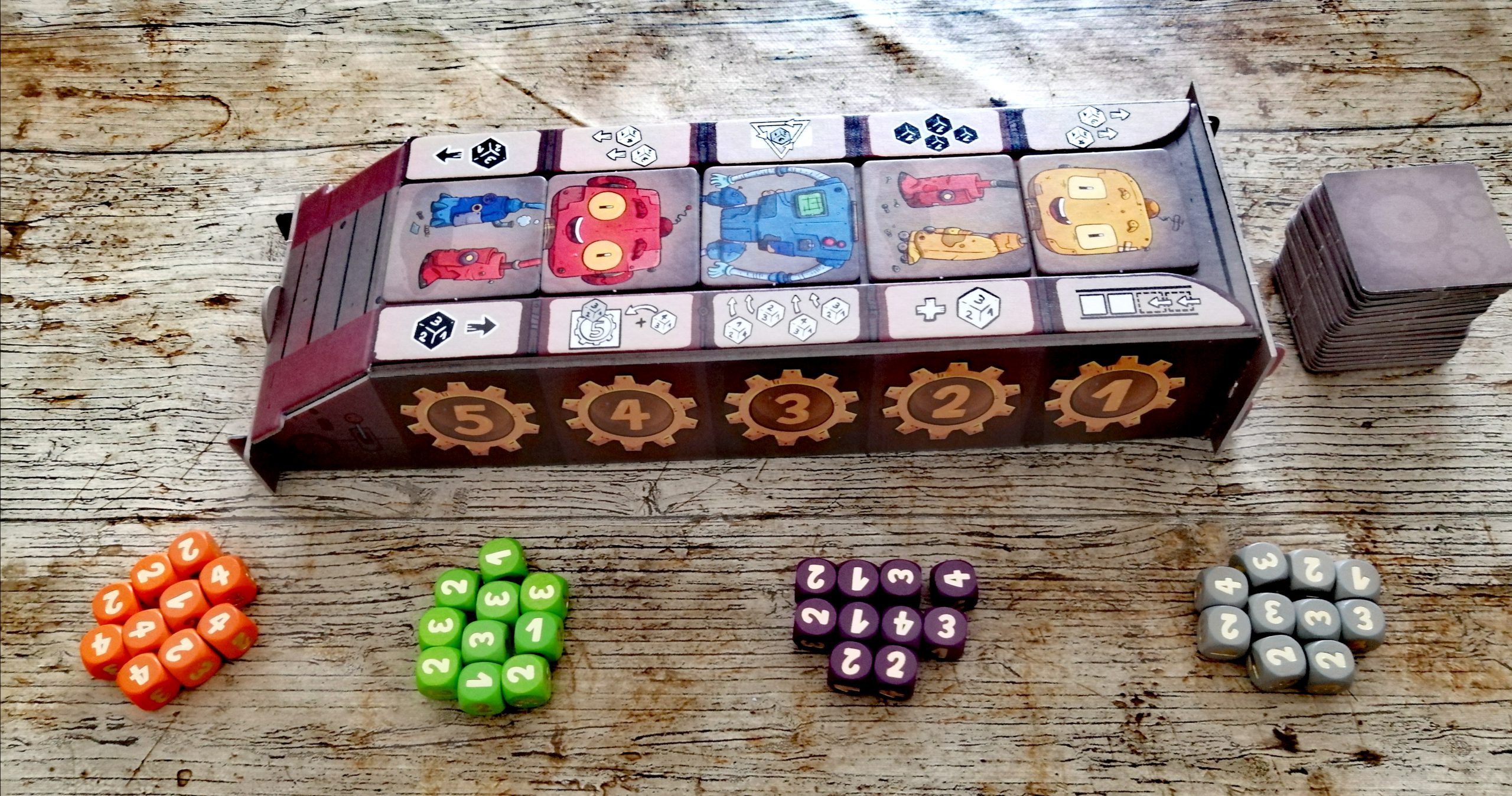 Das Fließband steht in der Mitte. Alle bekommen 10 Würfel einer Farbe. Das Fließband ist mit 5 Plättchen aufgefüllt. 