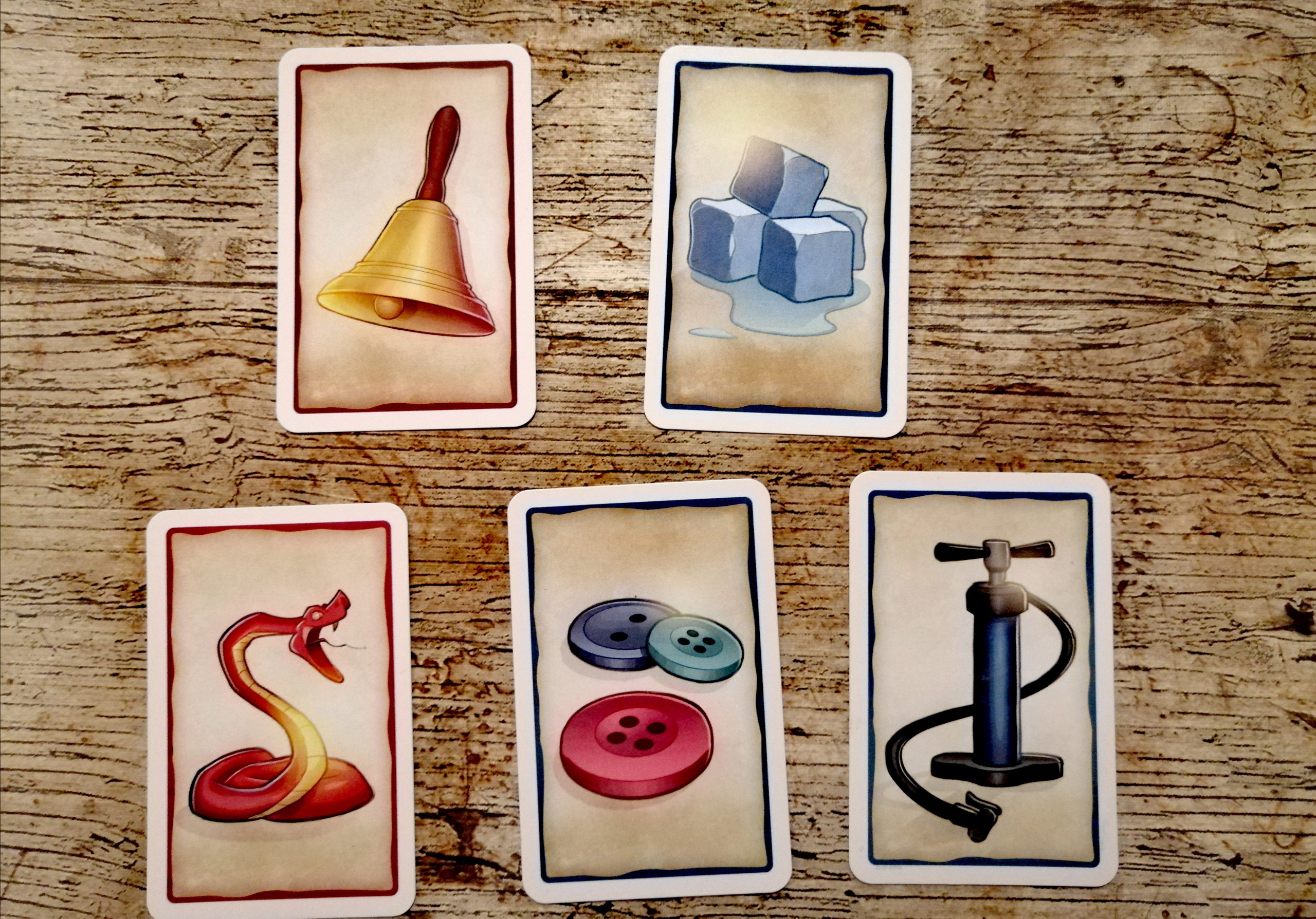 Es wurden 5 Karten ausgewählt. Eine Glocke, Eiswürfel, eine Schlange, bunte Knöpfe und eine Luftpumpe. Zwei Gegenstände passen. Welche?
