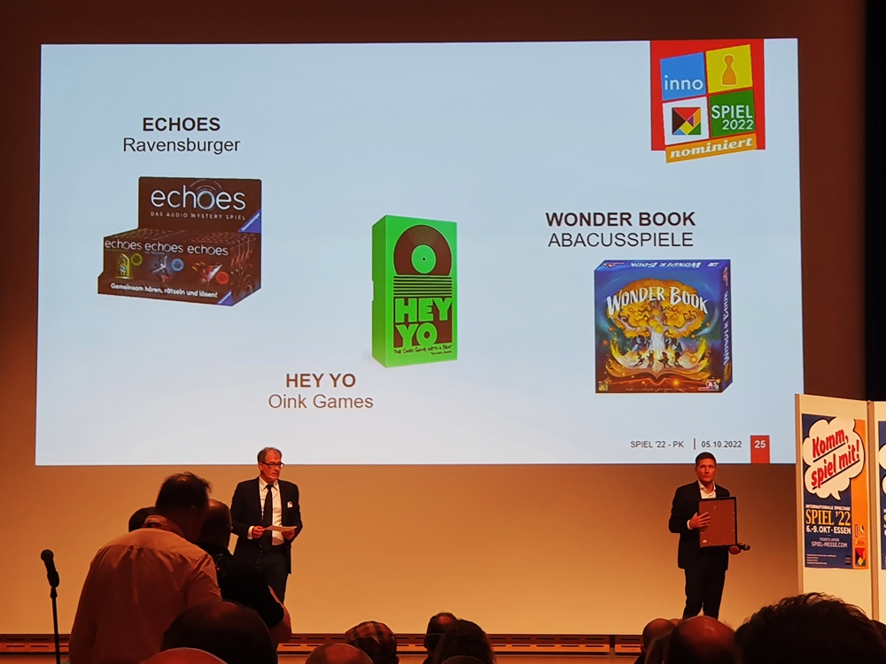 Podium mit Rednern, auf der Präsentation drei nominierte Spiele