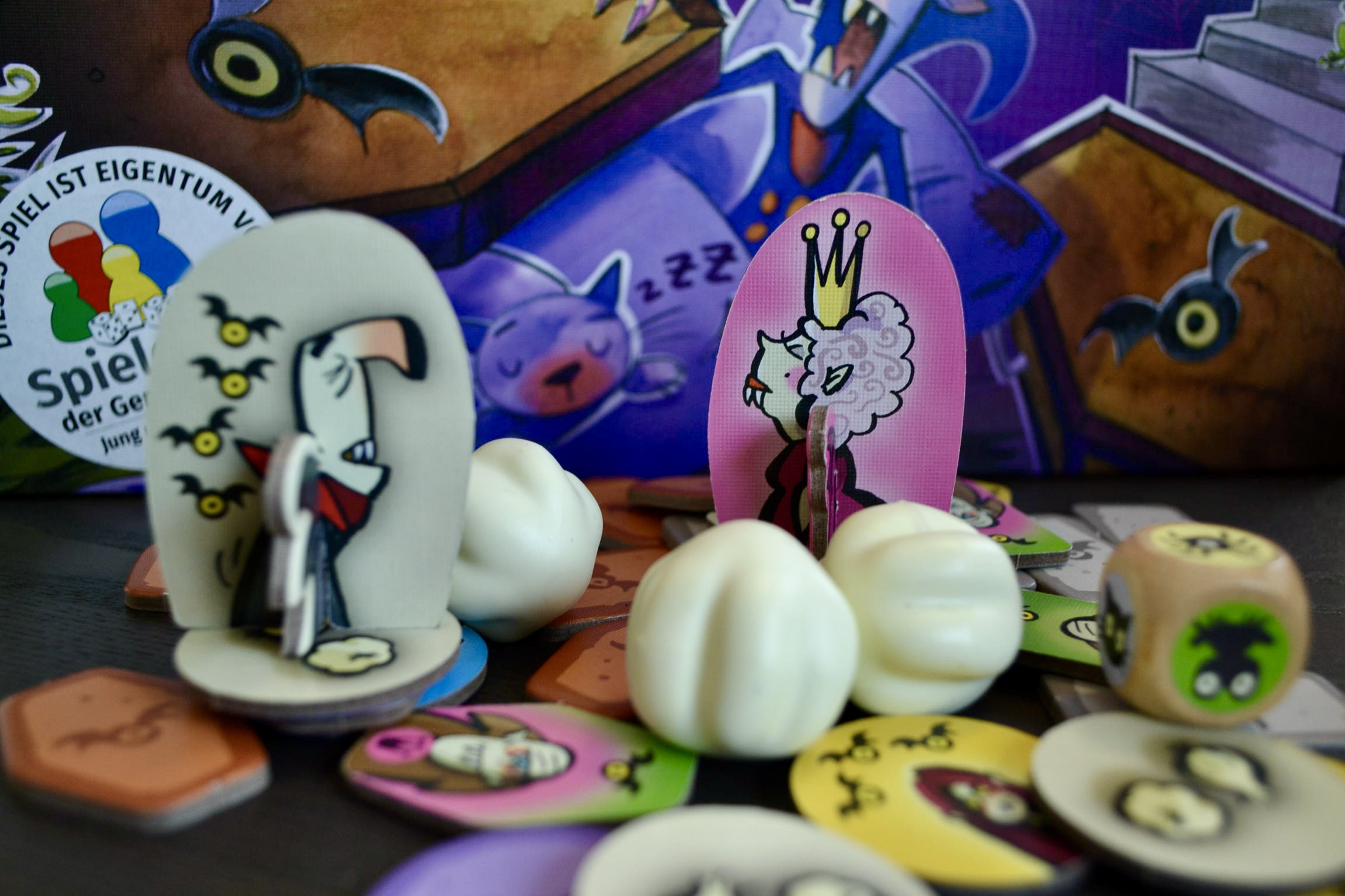 Man sieht das Spielmaterial des Spiels. U.a. die 3 Knoblauch-Knollen, mit denen man im Spiel hantieren muss