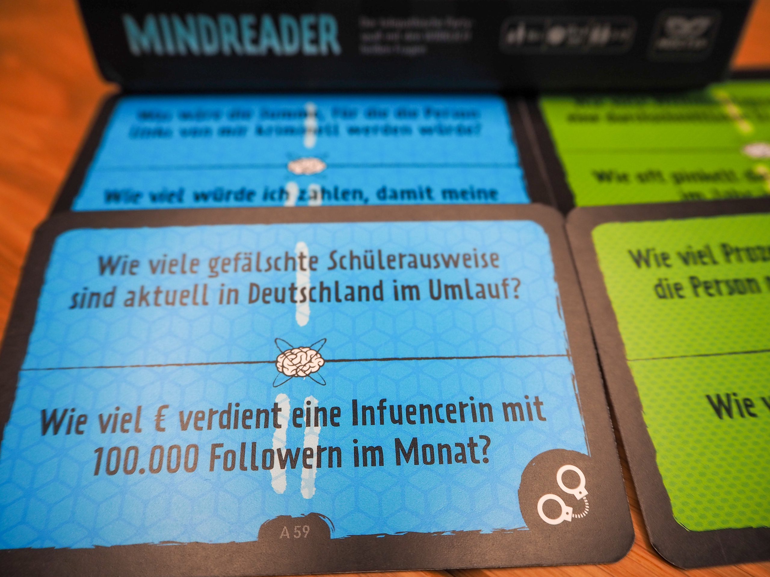 Im Hintergrund ist verschwommen die Spielschachtel zu sehen, während im Vordergrund eine blaue Karte im Fokus liegt.