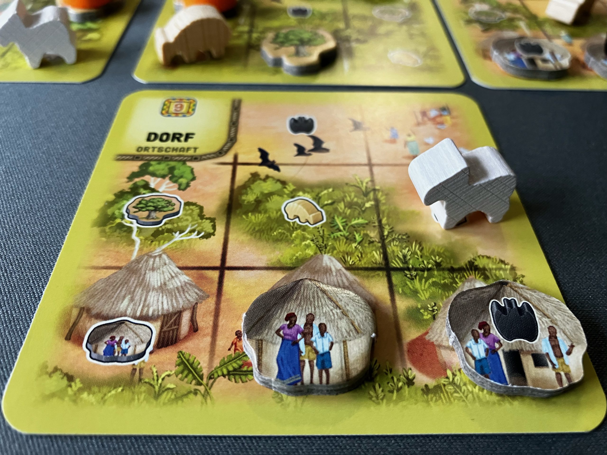 Quadratische Karte in der eigenen Auslage eine gebildete und eine nicht gebildete Familie stehen darauf, sowie eine Ziege