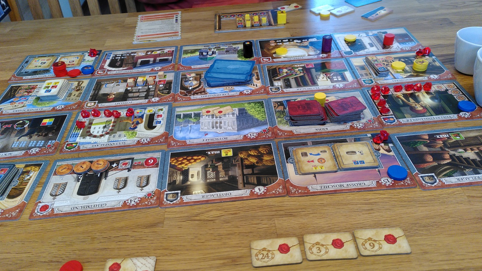 Blick über den Spielaufbau Istanbul mit der Erweiterung Brief und Siegel, unten die Aufträge der roten Spielerin