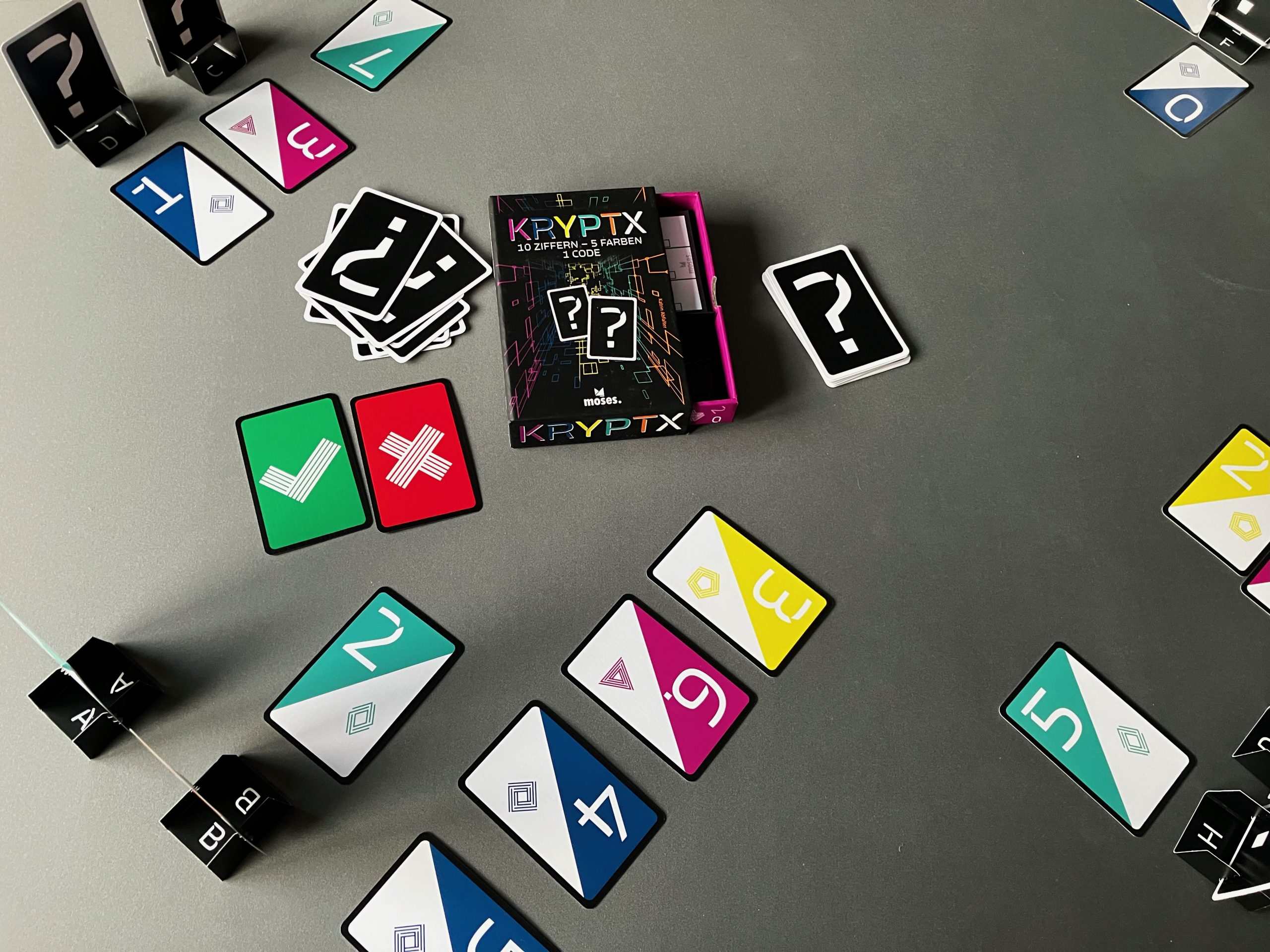 Spielszene einer Partie Kryptx zu viert. Karten liegen auf dem Tisch, die Spielschachtel in der Mitte
