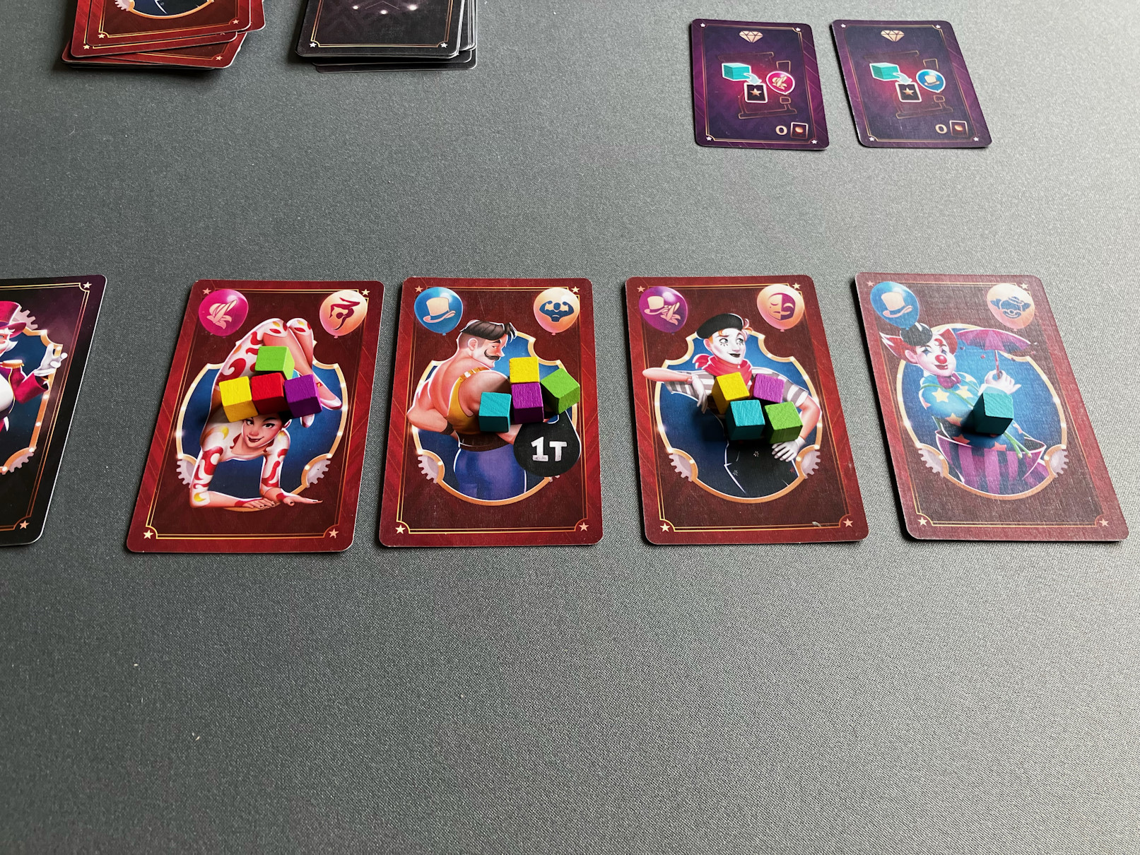 4 Artistenkarten liegen mit Würfeln darauf nebeneinander.