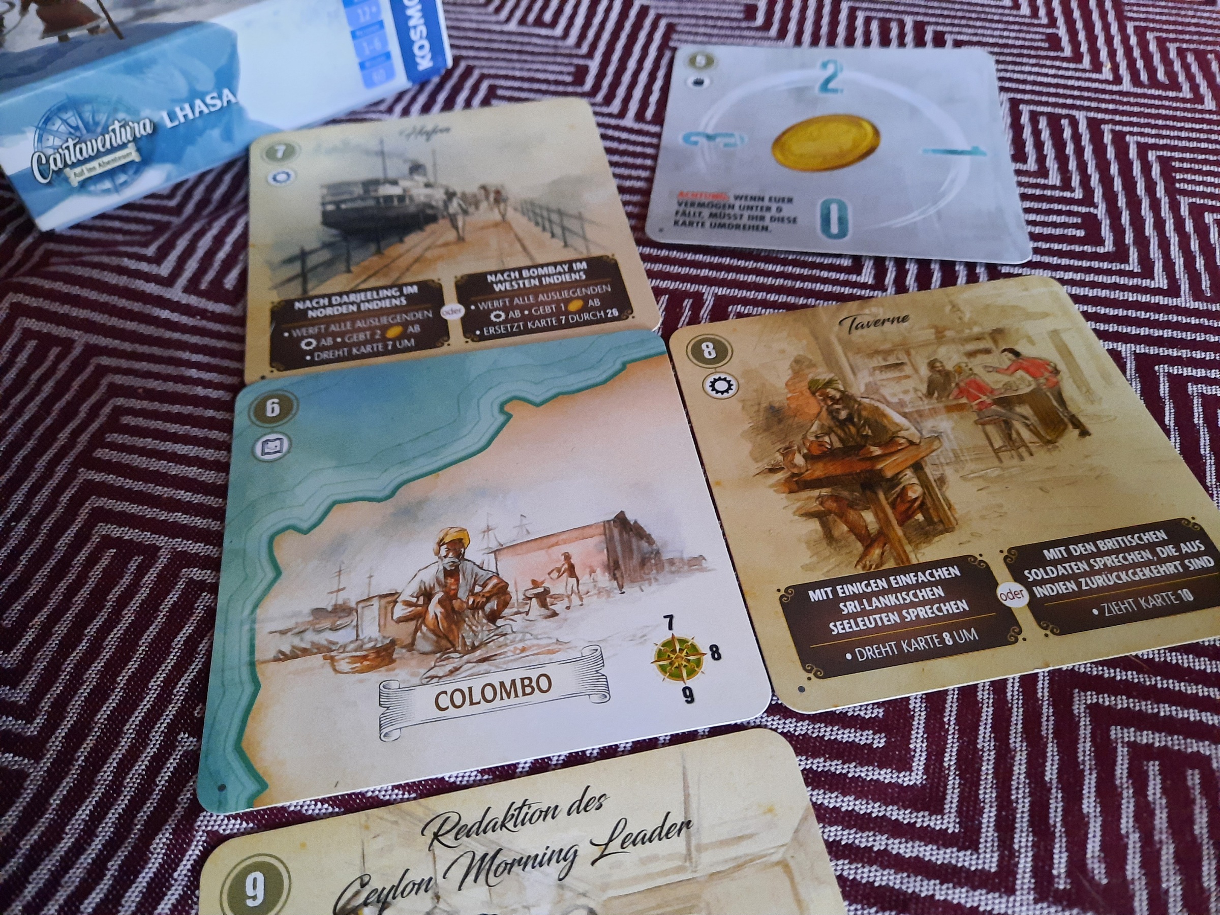 Mehrere Karten liegen auf dem Tisch. Auf den Karten sieht man Landkartenausschnitte, Bilder und Anweisungstexte