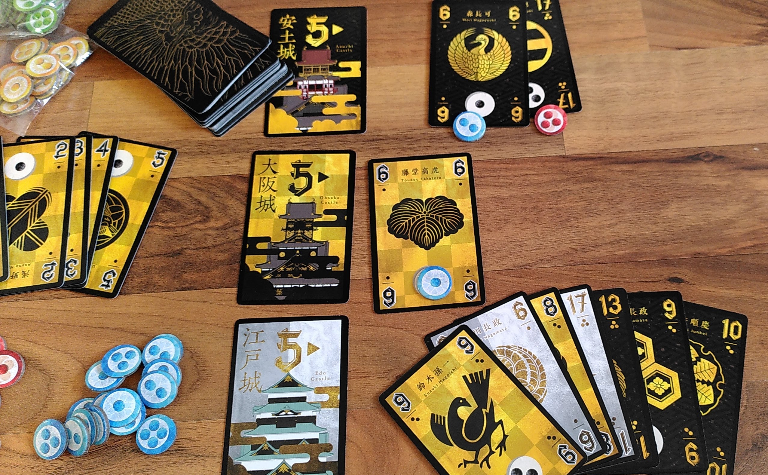 Spielaufbau für zwei Spielnde (rot und blau) mit 5 als Startzahlen in schwarz, silber und gold. Erste Spielzüge und Punkte