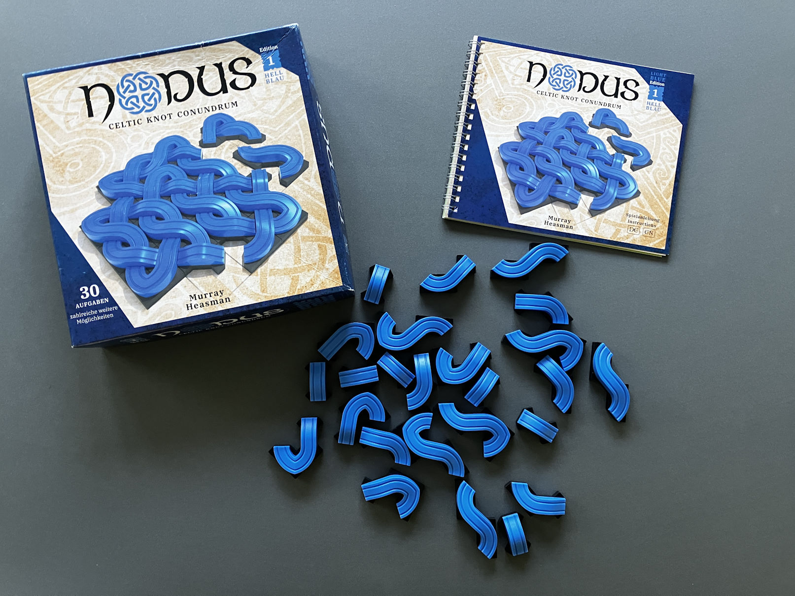 Spielschachtel und Puzzleteile liegen neben der Spielanleitung auf dem Tisch