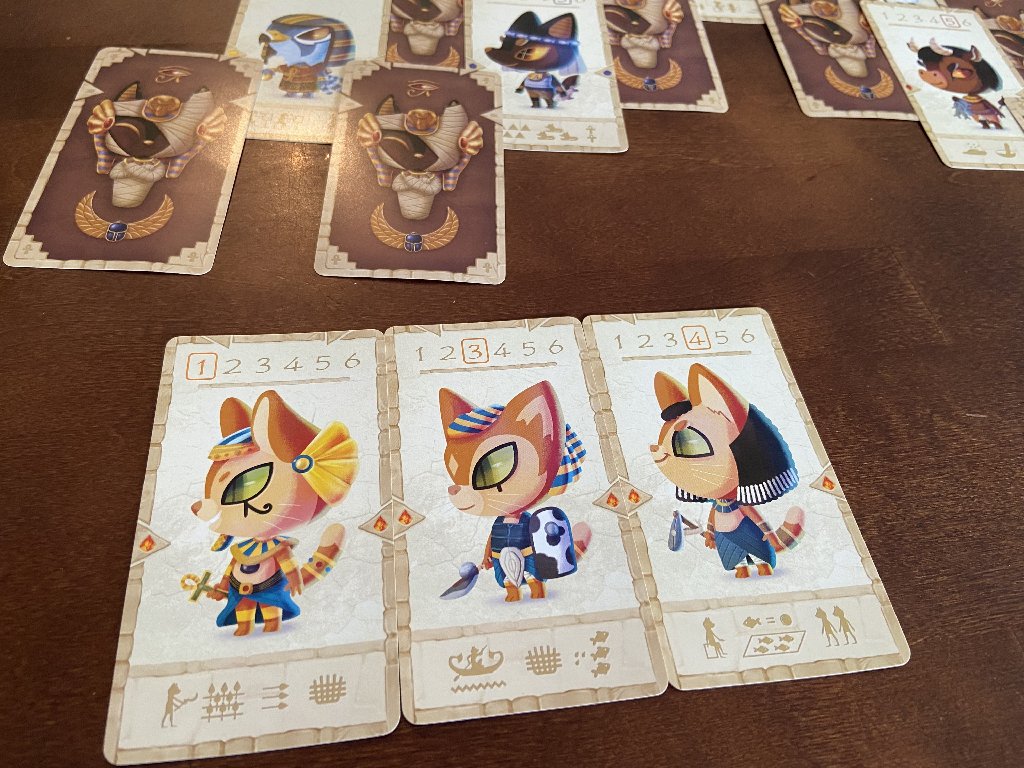 Drei Karten mit Katzengottheiten liegen nebeneinander auf dem Tisch.