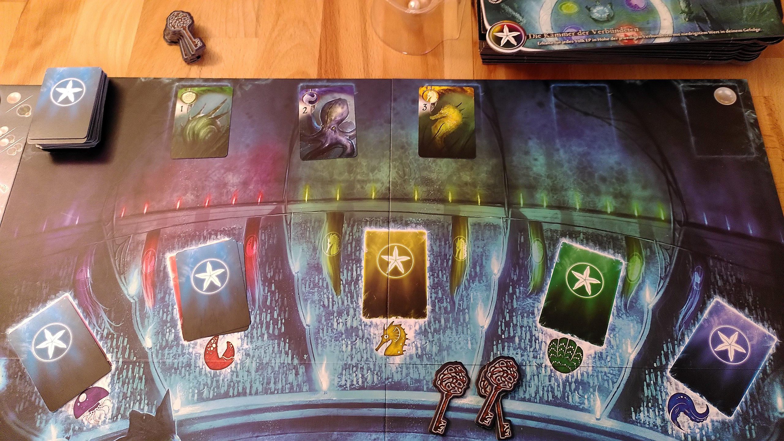 Auf dem Spielbrett ist oben Platz für die Tiefsee-Erkundung. Darunter gibt es einen Platz für jede Farbe der Ratsmitglieder, um sie verdeckt und farblich sortiert zu sammeln. 