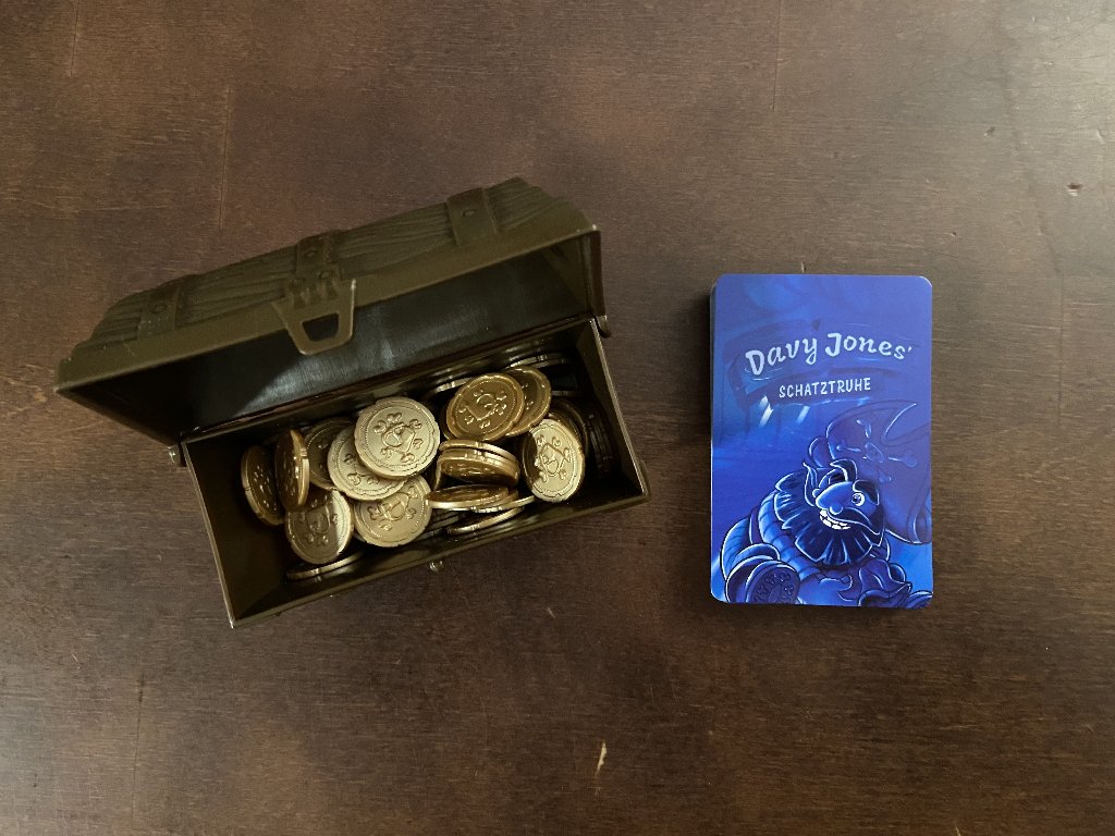 Plastik Schatzkiste mit goldenen Münzen und ein Kartenstapel