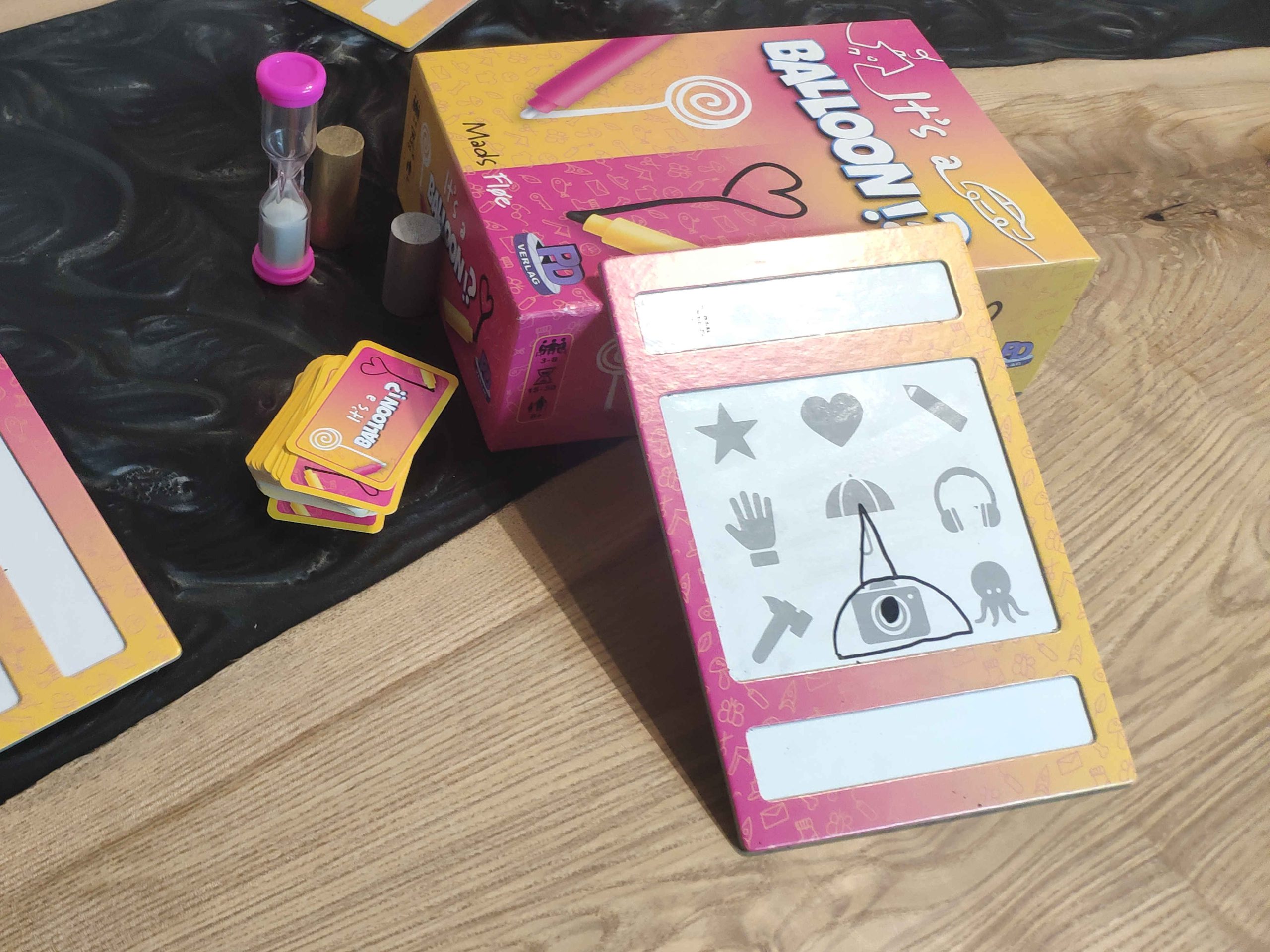 Das Spielmaterial liegt auf dem Tisch, eine kleine Sanduhr, Spielkarten und vorallem die abwischbaren Tafeln.