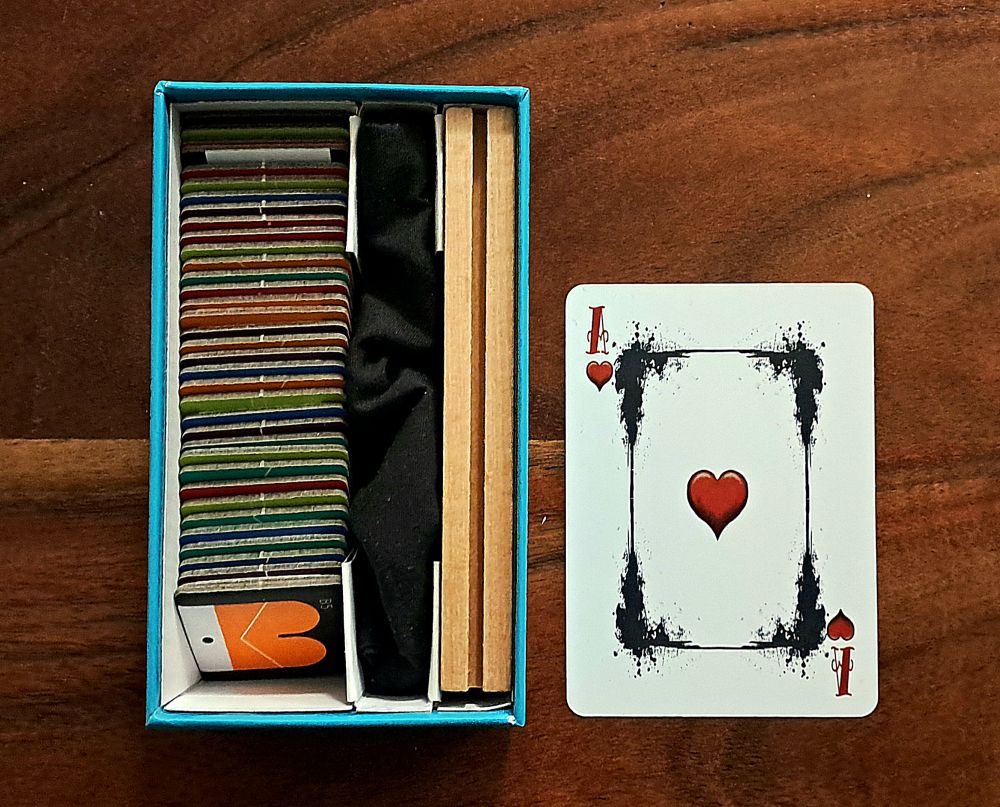 Der gefüllte Spielkarton im Größenvergleich zu einer üblichen Spielkarte