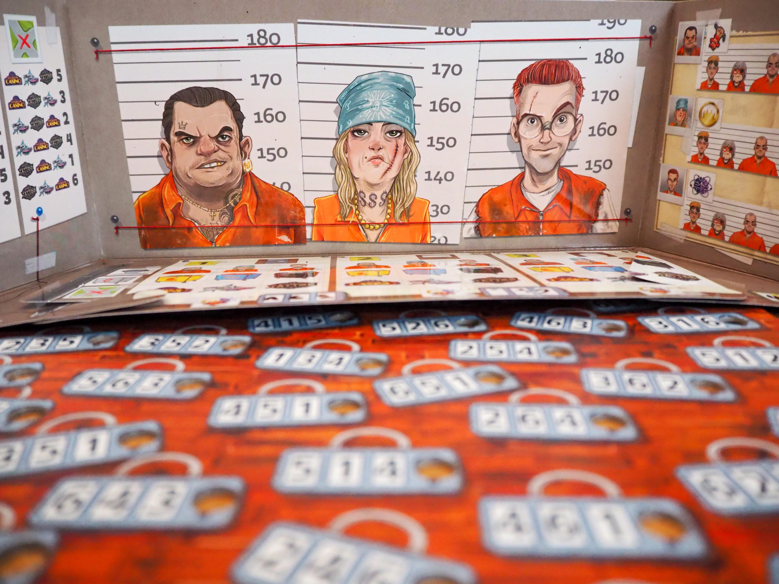 Unscharf im Vordergrund ist das Spielbrett mit den verschiedenen Schlössern und den diversen dreistelligen Nummern zu sehen. Scharf abgebildet ist der Spielerbogen, in dem ihr ankreuzen könnt, wer mit welchem Fluchtwäschewagen, durch welches Loch und mit welcher Hilfe, wohin geflohen ist.