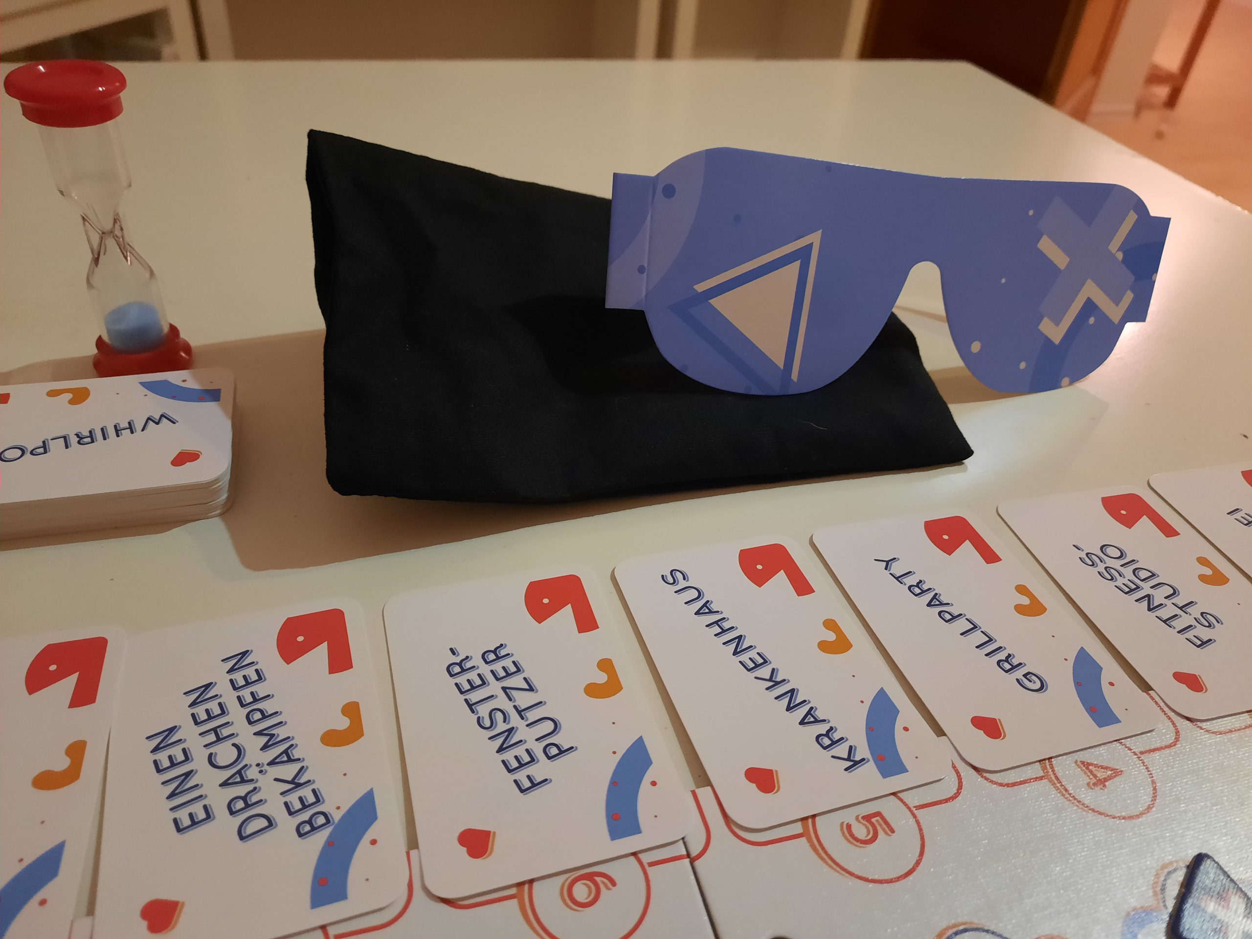 Karten mit Begriffen liegen einzeln neben dem Spielbrett aus. Ausserdem liegt noch die Spielbrille, der Nachziehstapel und die Sanduhr bereit.